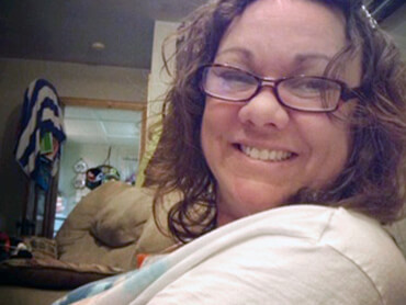 Melissa gives a big smile nestled in her bedroom at home.