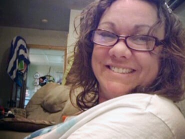 Melissa gives a big smile nestled in her bedroom at home.