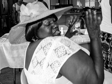 Charolette wearing a short-sleeved white dress and hat with wide brim.