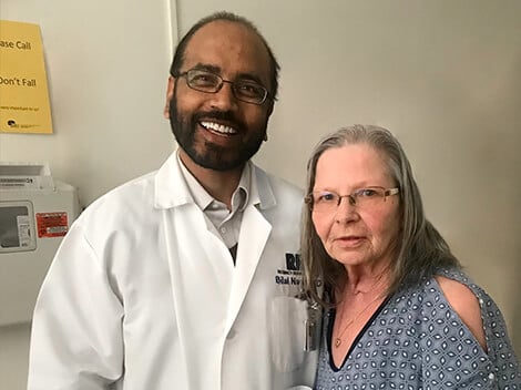 Debra stands next to her doctor in her hospital room.