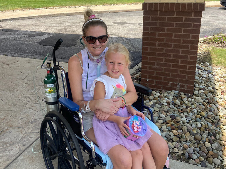 photo of Kelly Hirsh, sitting in a wheelchair, holding her daughter